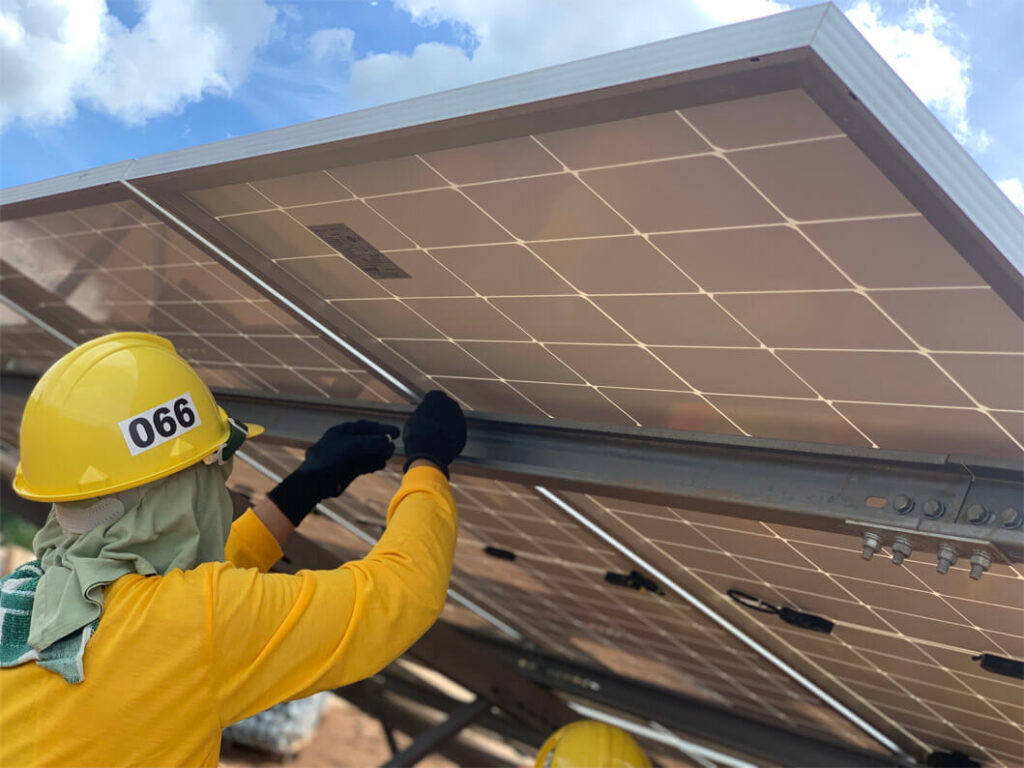 Worker wearing a yellow hard hat installing solar panel