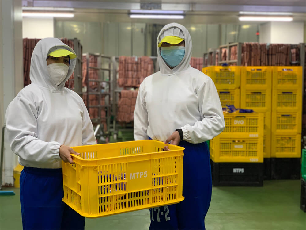 2 female factory worker holding a crate containing their product