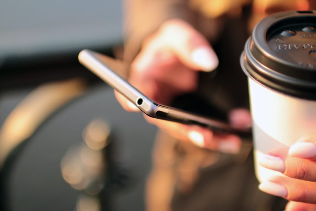 person holding a coffee cup and a phone