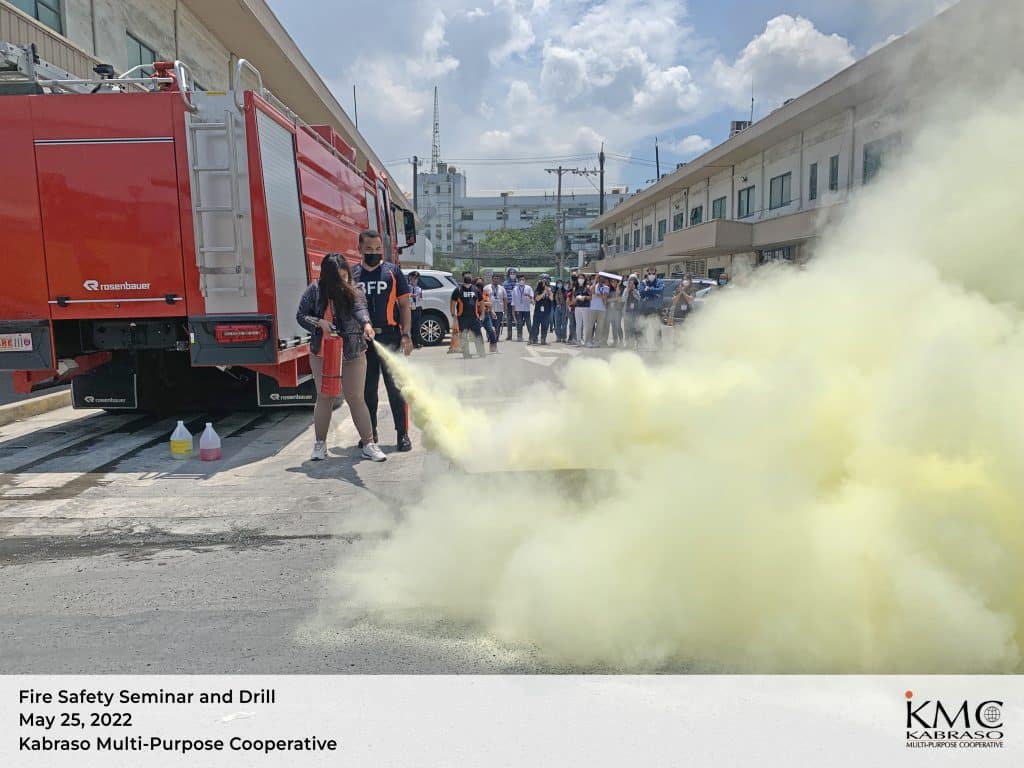 An employee using a fire extinguisher with the guidance of a BFP Personnel during the KMC Fire Safety Drill 2022