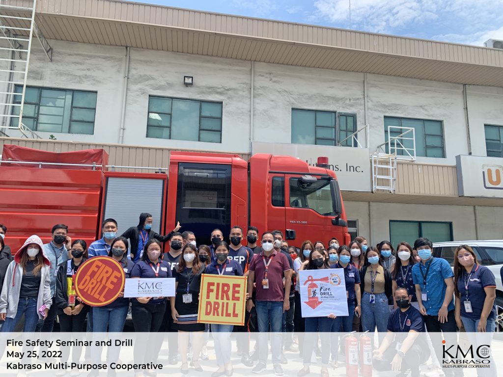 Employees holding placards infront of a firetruck after conducting KMC Fire Safety Awareness and Drill 2022