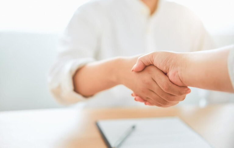 2 person wearing white shaking hands after an agreement