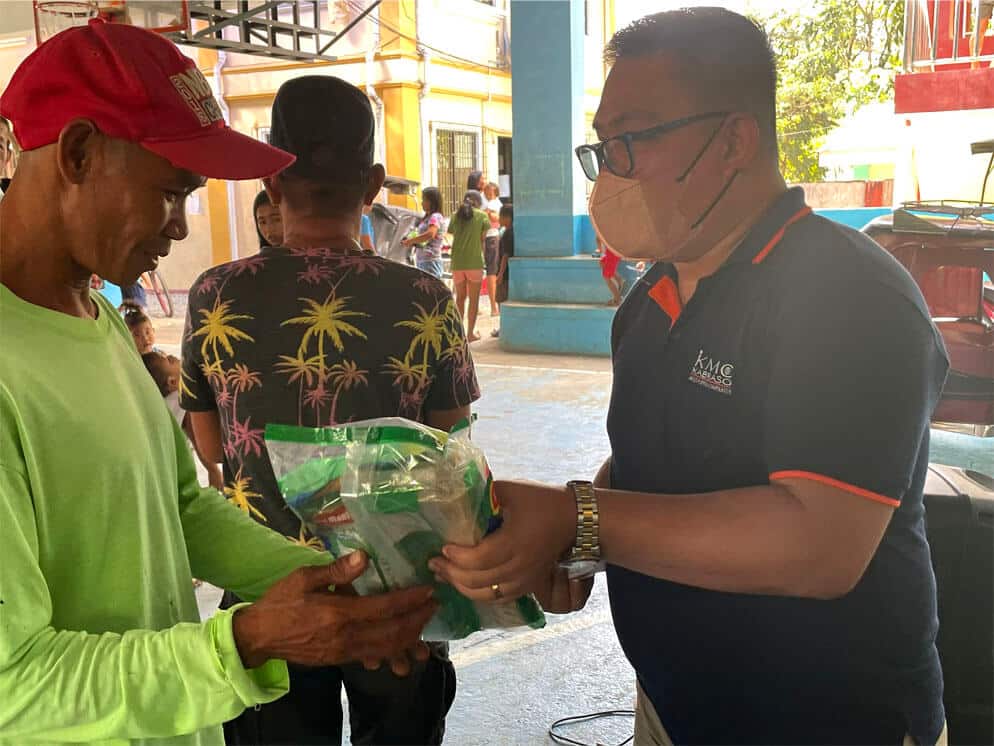 A member of KMC giving away Christmas food pack to a man