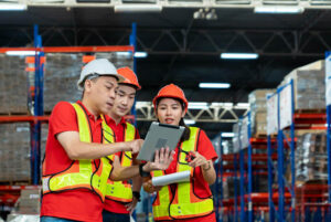 A man showing somethingonthe ipad to the 2 other employees of logistics and warehouse