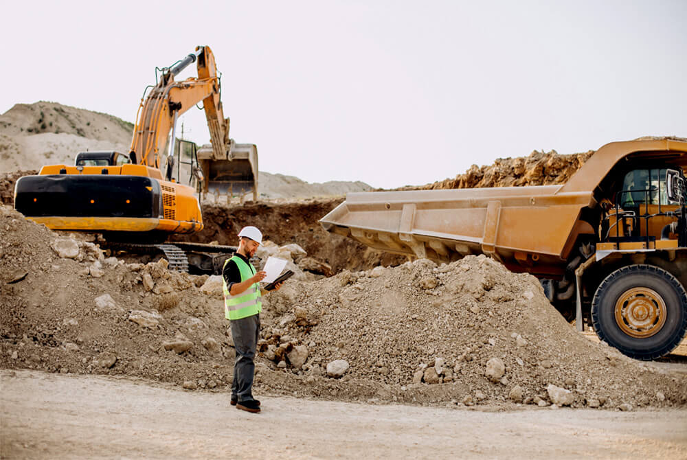 Male worker in a mining site with bulldozers on the background