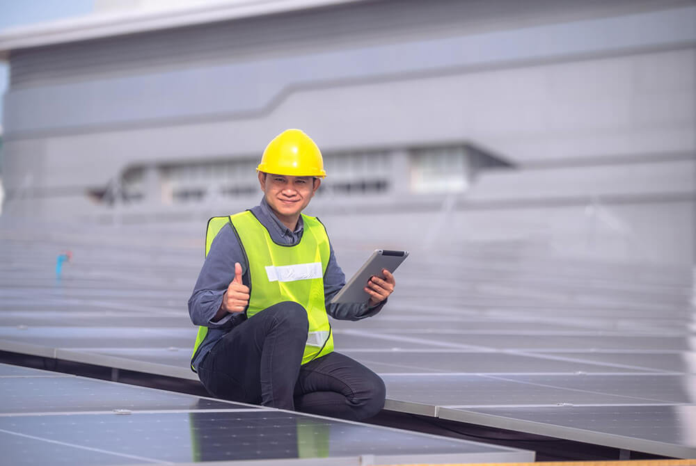 A man holding an ipad, doing a thumbs up at a solar power plant