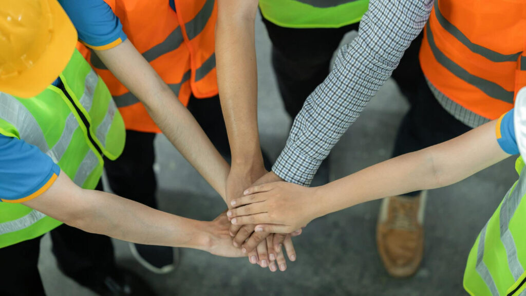 Constrcution involved workers placing their hands together in the middle to show teamwork