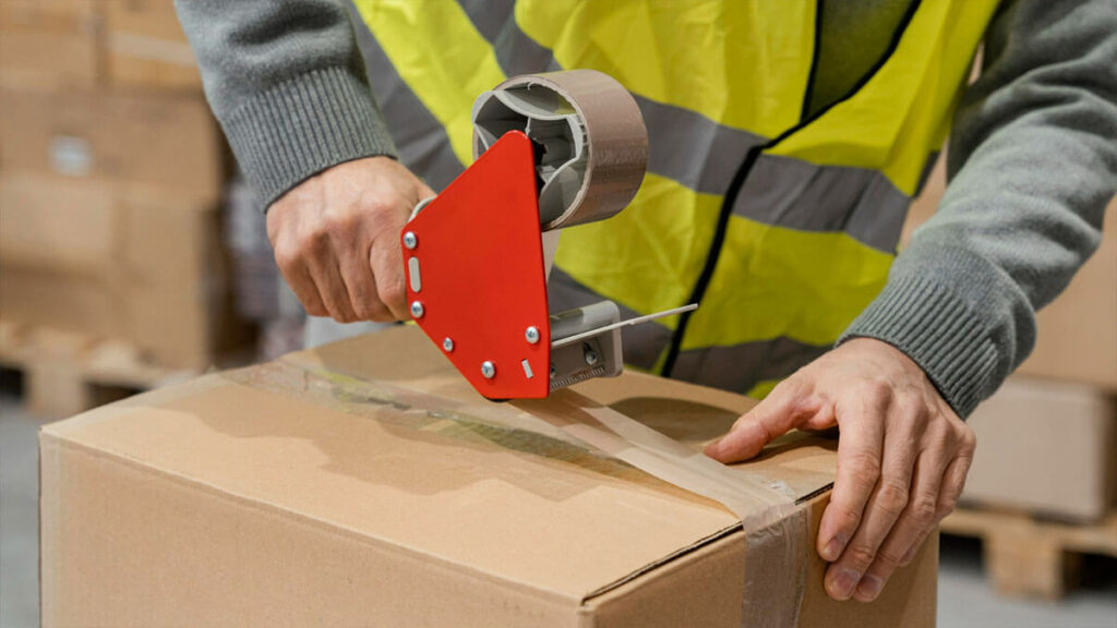 warehouse worker using packaging tape to seal the packages.