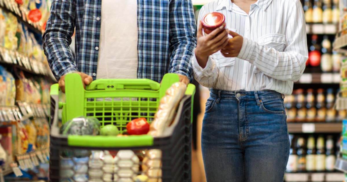 man in a checkered long-sleeved shirt is pushing a cart, and there is a woman standing beside him