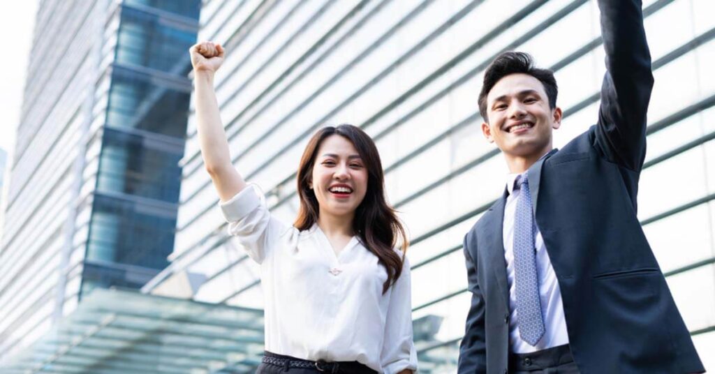 A young woman and a young man cheering their success, lifting their hands