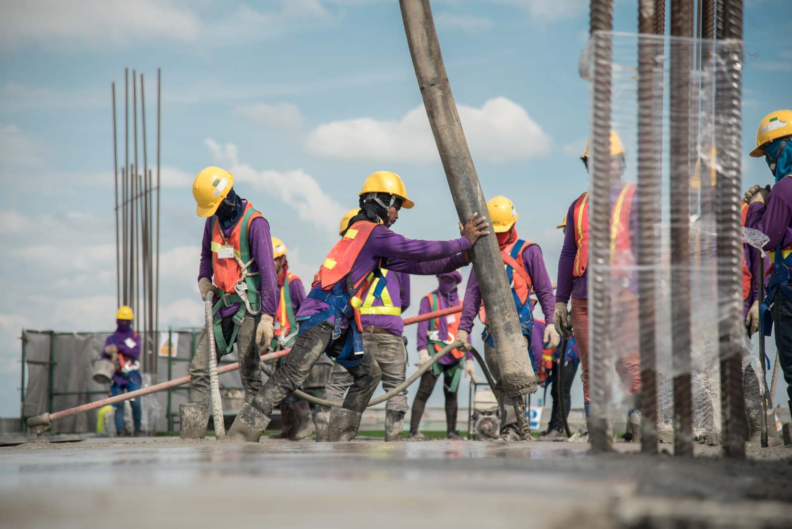 group of construction workers pouring concrete over construction project wearing PPEs