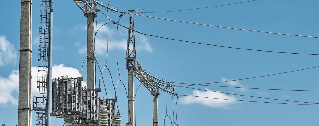 high voltage electrical power transmission infrastructures standing against blue sky with minimal clouds