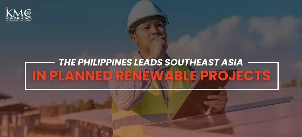 A construction worker wearing a hard hat and reflective vest stands beside solar panels, holding a tablet and looking thoughtfully into the distance. Text overlay reads: ‘The Philippines leads Southeast Asia in planned renewable projects.’ The KMC Kabraso Multi-Purpose Cooperative logo appears in the top left corner